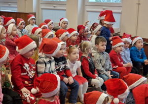 grupa dzieci w czerwonych ubrankach i czapkach Mikołaja