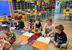 dzieci w sali przedszkolnej z ksiązkami przed sobą