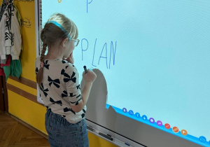 dziewczynka pisząca na tablicy interaktywnej