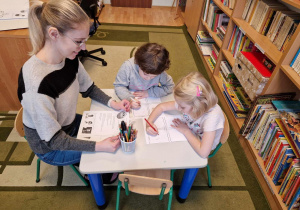 dzieci przy stoliku wykonujące rysunki, nauczycielka