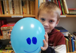 chłopiec z balonem z narysowana "buzią"