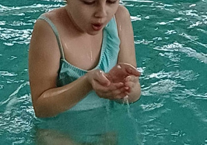 dziewczynka w basenie dmuchające w dłonie