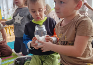 chłopcy trzymają skoik ze śniegiem