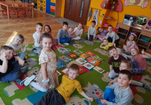 grupa pzredszkolaków na dywanie, rozłożone książki