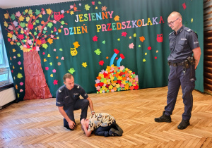 policjanci, przedszkolak w "pozycji bezpiecznej"